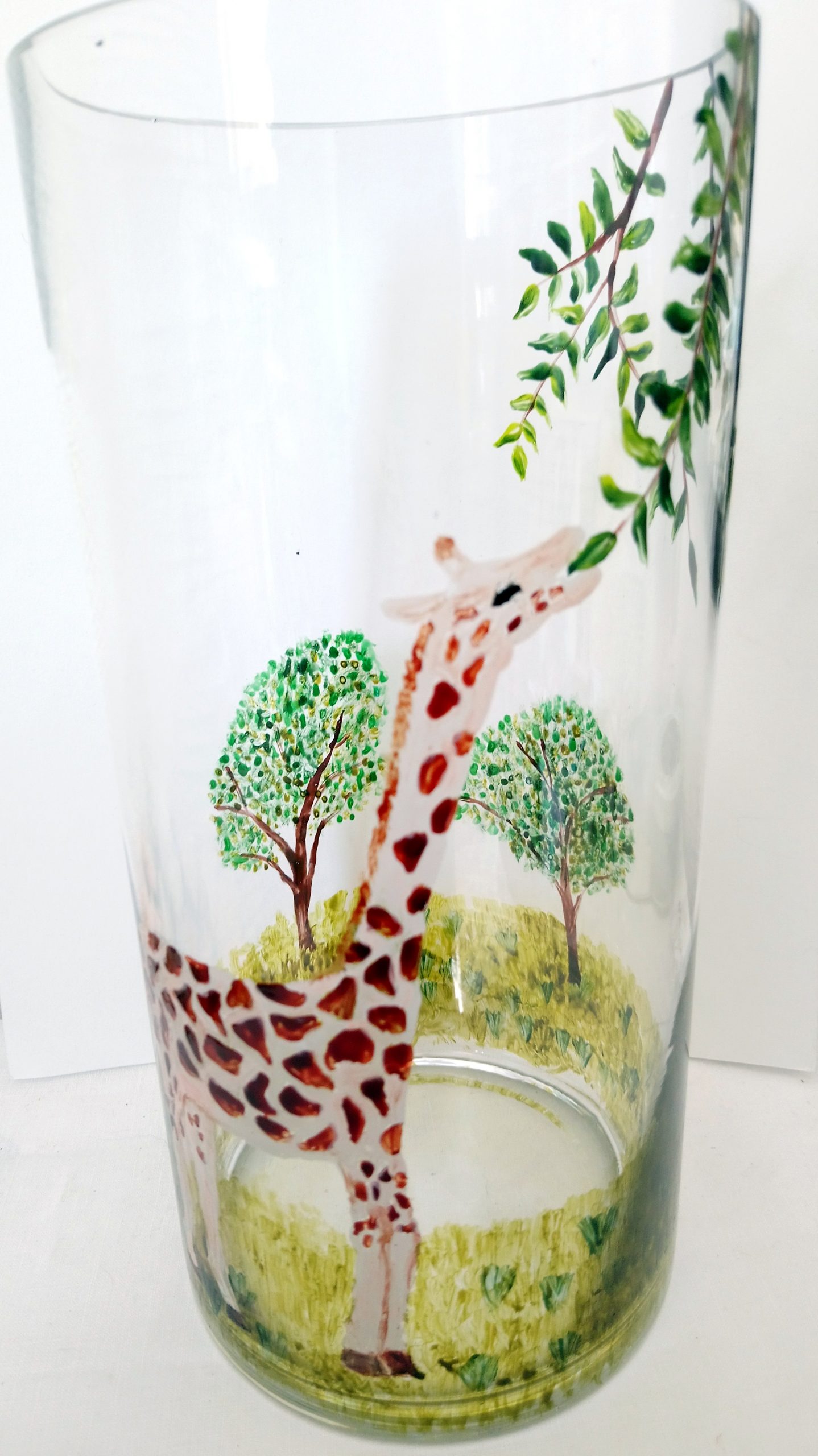 A Giraffe vase gift hand painted with a giraffe reaching up to leaves on a tree